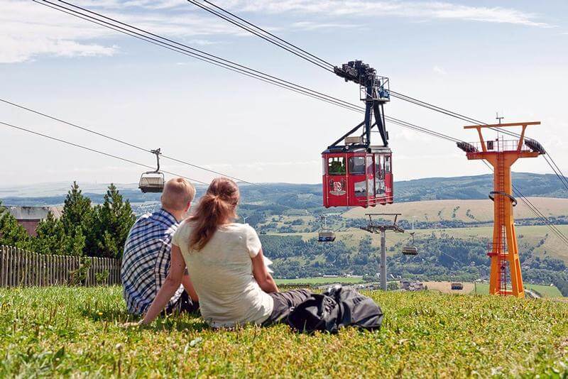 Oberwiesenthal a přilehlý areál. Na obrázku je historická lanovka a výhled z kopce dolů na město.